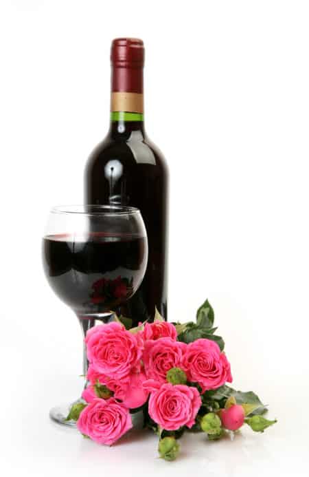 beautiful rose and bottle of wine on a white background
